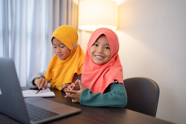 Feliz sorridente jovem garoto muçulmano com laptop juntos