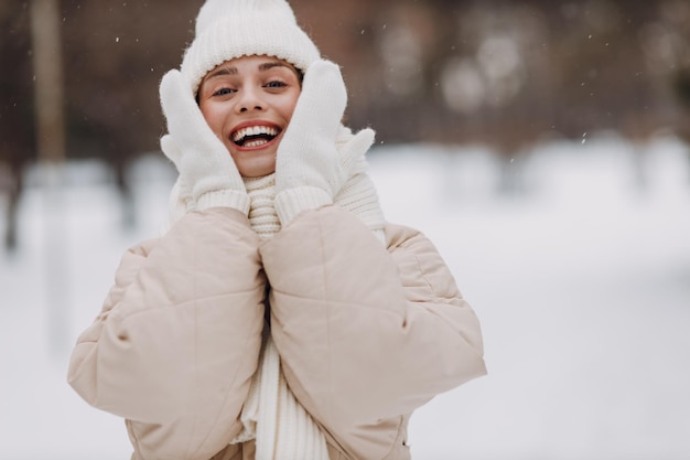 Foto feliz sorridente jovem retrato de mulher vestida casaco lenço chapéu e luvas gosta do tempo de inverno no parque de inverno coberto de neve