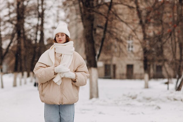 Feliz sorridente jovem retrato de mulher vestida casaco lenço chapéu e luvas gosta do tempo de inverno no parque de inverno coberto de neve