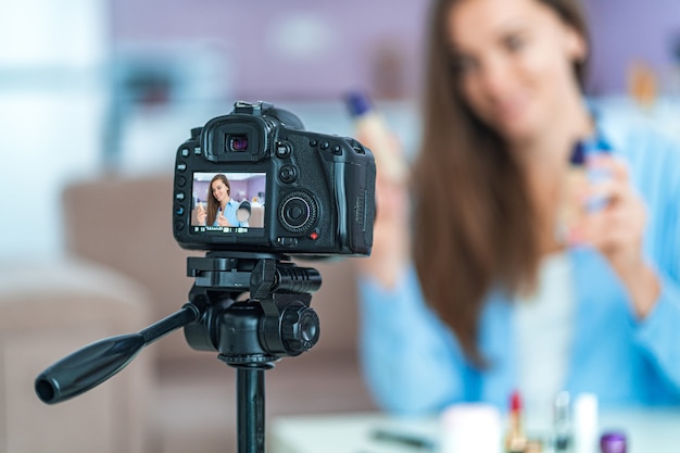 Foto feliz sorridente jovem vídeo blogger durante a gravação de seu blog de beleza sobre maquiagem e cosméticos em casa. blogs e transmissão ao vivo com o público