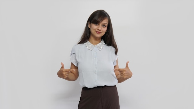 Foto feliz sorridente mulher asiática apontando com dois dedos em seu vestido em branco