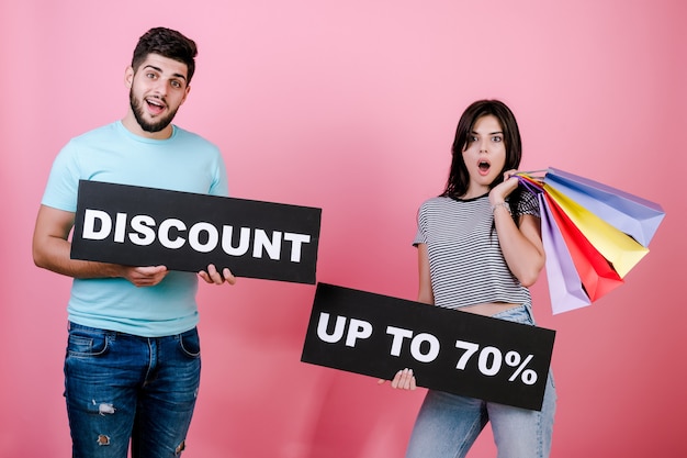 Feliz sorrindo bonito casal homem e mulher com desconto até 70% de sinal e sacolas coloridas