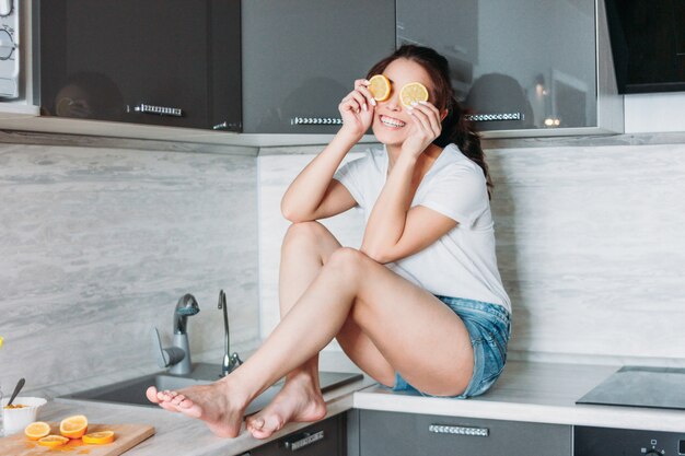 Feliz, sorrindo, bonito, longo, cabelo, menina, engraçado, mulher jovem, com, limão, em, cozinha