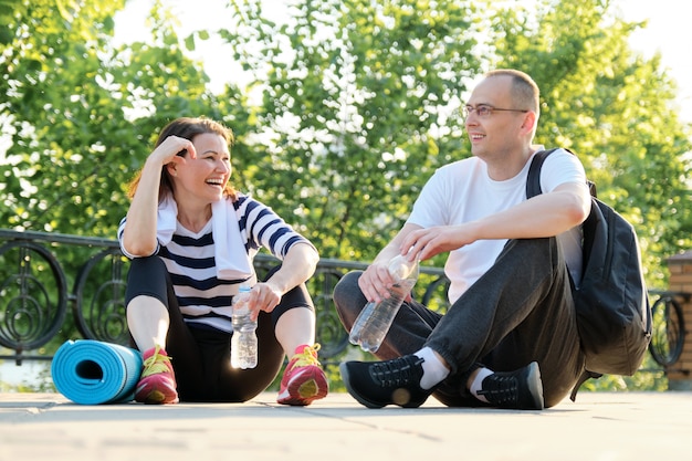 Feliz sorrindo Casal maturo sentado no parque, conversando descansando depois de fazer esportes