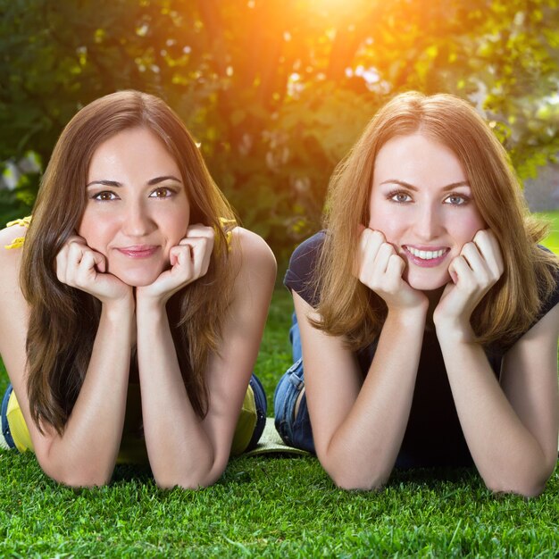 Feliz sorrindo jovens mulheres deitada na grama