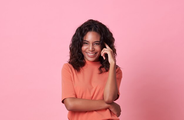 Feliz sorrindo linda mulher africana, olhando para a câmera, vestindo camiseta laranja casual na rosa.