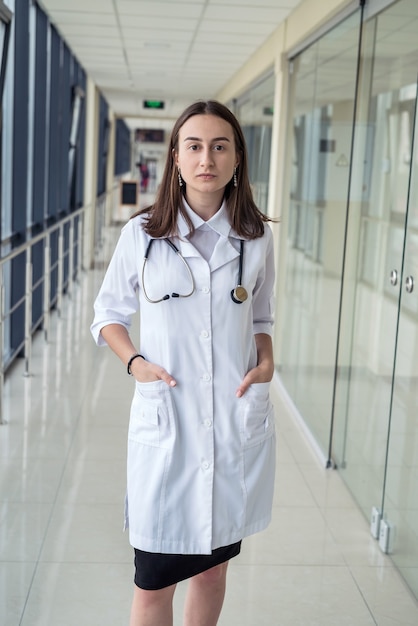 Feliz sozinha jovem enfermeira no corredor do hospital. Conceito de medicina