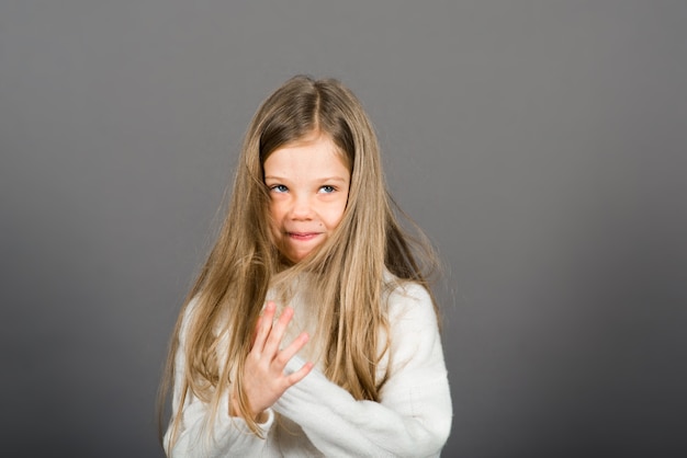 Feliz surpresa linda criança menina olhando para a câmera em fundo cinza. emoções humanas