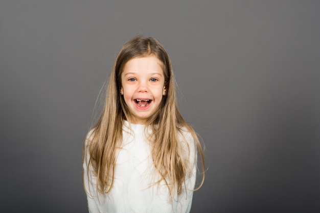 Feliz surpresa linda criança menina olhando para a câmera em fundo cinza. Emoções humanas