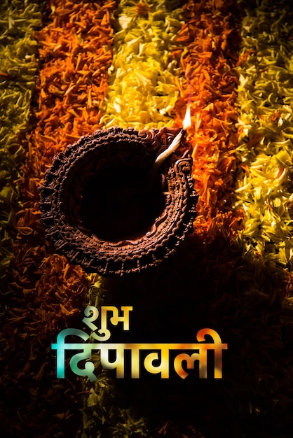 Feliz tarjeta de felicitación de diwali hecha con una lámpara de barro tradicional de la India colocada sobre el rangoli de pétalos de caléndula, de cerca y el enfoque selectivo