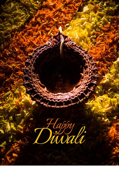 Foto feliz tarjeta de felicitación de diwali hecha con una lámpara de barro tradicional de la india colocada sobre el rangoli de pétalos de caléndula, de cerca y el enfoque selectivo