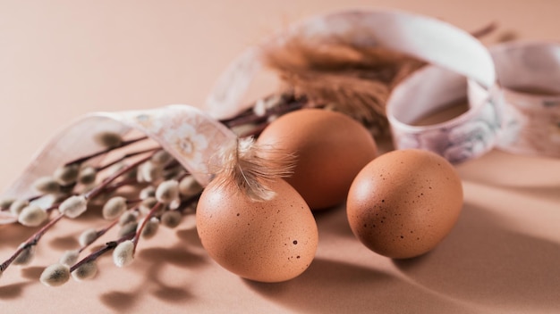 Feliz tarjeta de Pascua con huevos de color natural y plumas sobre fondo beige