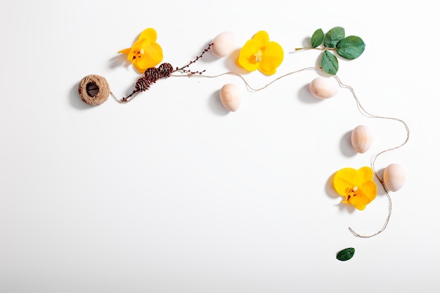 Feliz tarjeta de Pascua con huevos de madera de cuerda y flores de orquídeas sobre fondo blanco