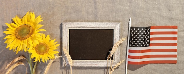 Feliz texto de Ação de Graças no quadro-negro Banner com bandeira dos EUA com girassóis e decorações de outono Flat lay no festival de colheita americana têxtil bege com decoração tradicional de outono
