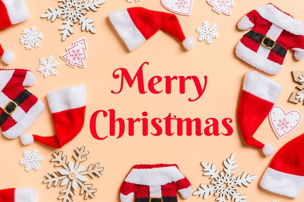 Feliz texto de Natal Vista superior das decorações de Natal e chapéus de Papai Noel em fundo laranja Feliz conceito de férias com espaço de cópia