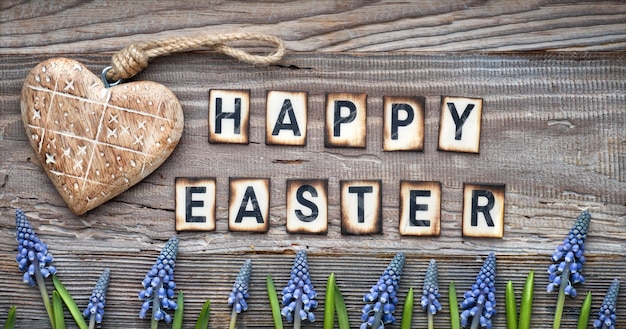 Feliz texto de Pascua en madera rústica con corazón de madera maciza y flores de jacinto azul