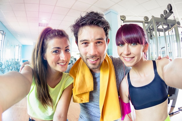 Feliz trío de amigos activos tomando selfie en el centro de estudio de entrenamiento de gimnasio