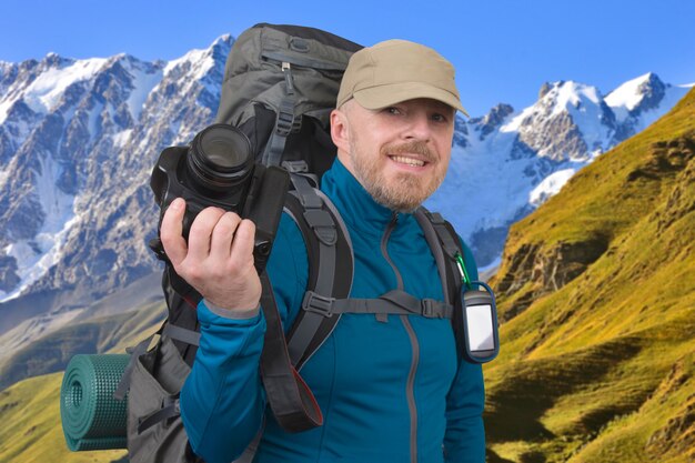 Feliz turista barbudo con cámara en la superficie de hermosas montañas