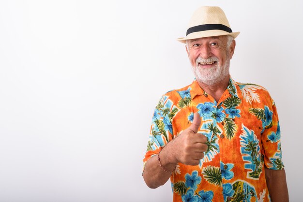 Feliz turista barbudo senior hombre sonriendo mientras da pulgar hacia arriba y con sombrero en blanco