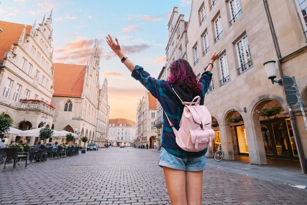 Foto feliz turista visitando a rua prinzipalmarkt e admirando os prédios antigos da arquitetura da cidade em munster alemanha