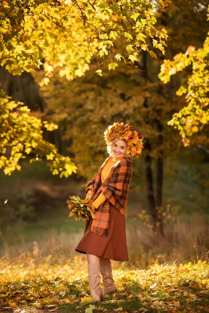 Feliz vejez. Anciana alegre con hojas de otoño amarillas en sus manos, caminando en el parque.