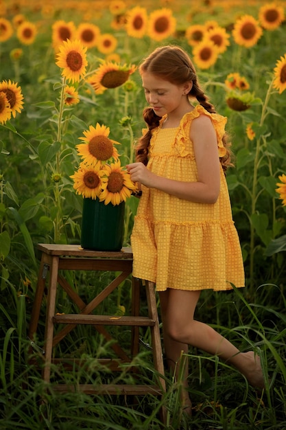 Feliz verano en el campo alegre niña traviesa pelirroja con coletas en un campo de girasoles al atardecer