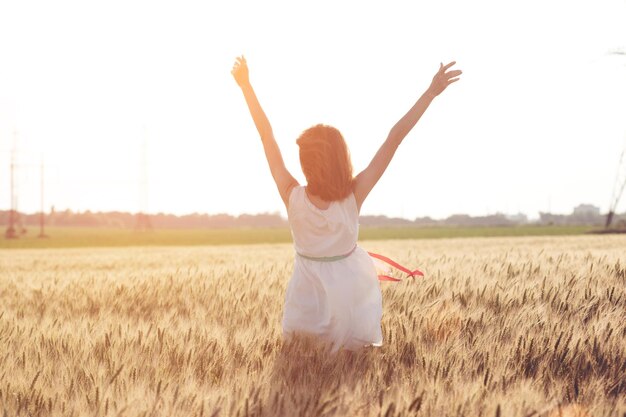 Feliz verão e liberdade. Linda garota no campo de trigo em um dia ensolarado