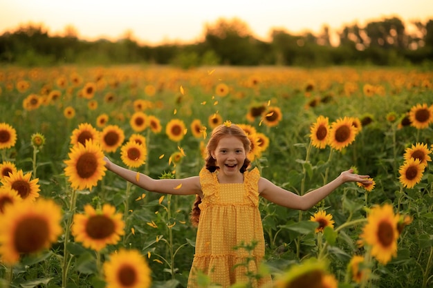 Feliz verão na zona rural alegre ruiva travessa com tranças em um campo de girassóis ao pôr do sol