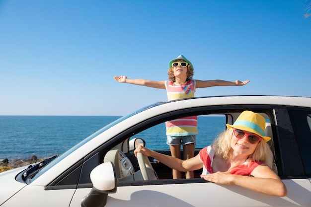 Feliz viaje familiar en coche en el mar Madre e hijo divirtiéndose en cabriolet azul Concepto de vacaciones de verano