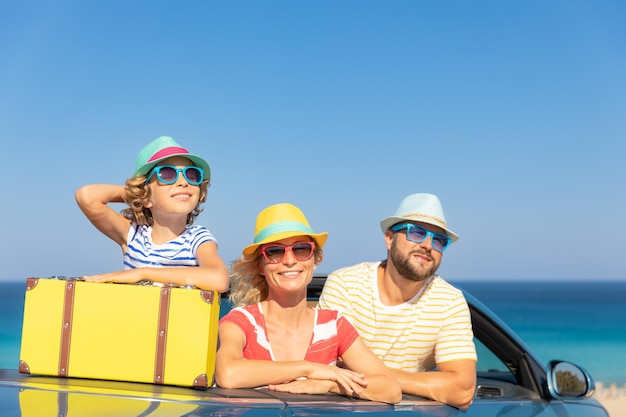 Feliz viaje familiar en coche en el mar Madre padre e hija divirtiéndose en cabriolet azul Concepto de vacaciones de verano
