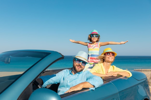 Feliz viaje familiar en coche en el mar Madre padre e hija divirtiéndose en cabriolet azul Concepto de vacaciones de verano