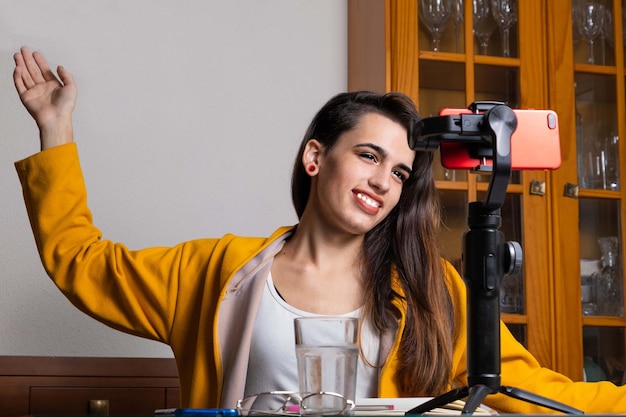 Feliz vlogger feminina transmitindo ao vivo da sala de estar usando smartphone