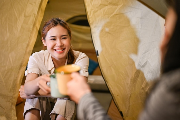 Felizes amigos asiáticos aproveitam a noite de acampamento juntos Conceito de acampamento