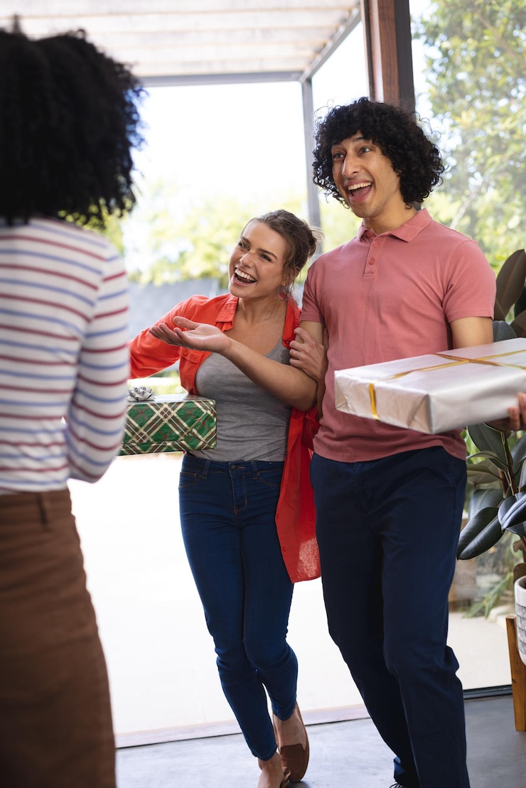 Foto felizes amigos diversos cumprimentando na porta com presentes no natal. conceito de natal, celebração, amizade, inclusão e estilo de vida.