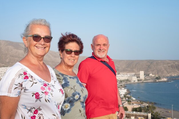 Felizes amigos idosos maduros apreciando a paisagem da colina desfrutando de férias e bons momentos