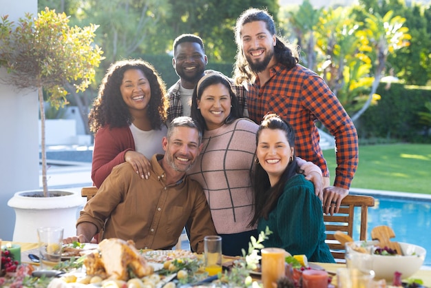 Foto felizes amigos masculinos e femininos diversos posando durante a refeição de celebração de ação de graças no jardim ensolarado