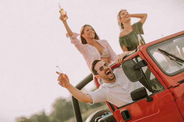 Felizes amigos se divertindo no carro conversível em férias