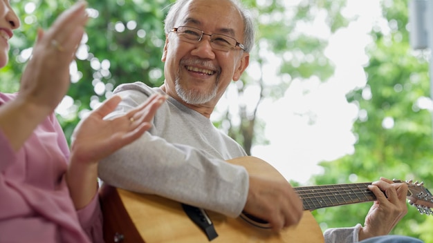 Felizes avós sênior tocando violão e cantando músicas se divertindo