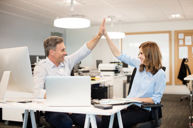 Felizes colegas de trabalho dando mais cinco uns aos outros