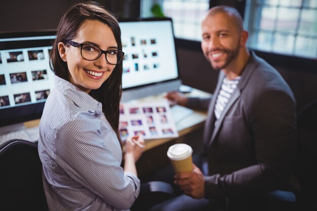 Felizes colegas sentados na mesa do computador no escritório criativo