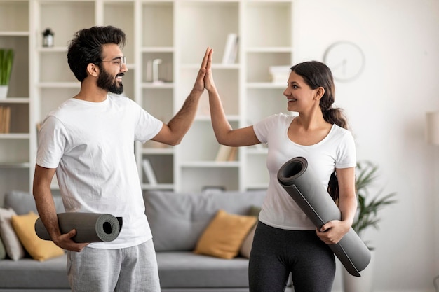 Felizes cônjuges indianos dando mais cinco após um treinamento de ioga bem-sucedido em casa