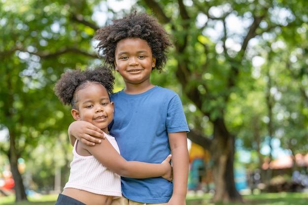 Felizes crianças adoráveis, menino afro-americano e garotinha sorrindo e abraçando juntos no parque