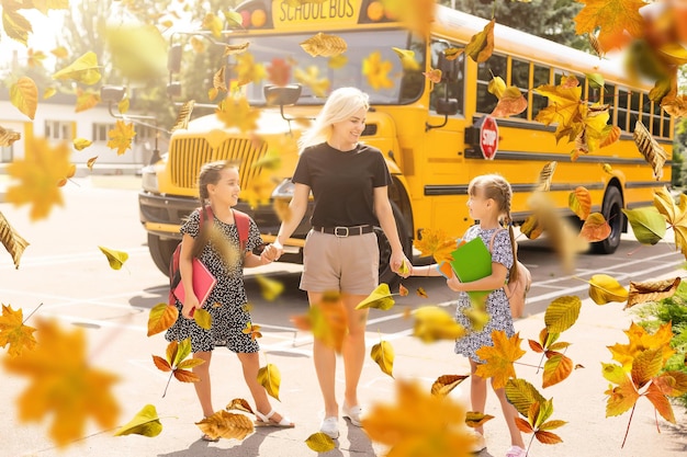 Felizes crianças caucasianas do ensino fundamental correndo de ônibus amarelo no primeiro dia de setembro. educação e volta às aulas no outono caem. criança animada no pátio da escola ao ar livre. cabeçalho do banner da web.