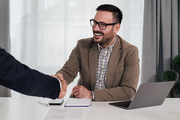 Felizes empresários apertando as mãos em uma reunião bem-sucedida no escritório corporativo