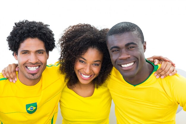 Felizes fanáticos do futebol brasileiro em amarelo sentado no sofá