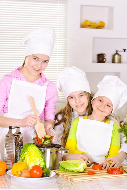 Felizes garotas bonitas cozinhando prato de legumes