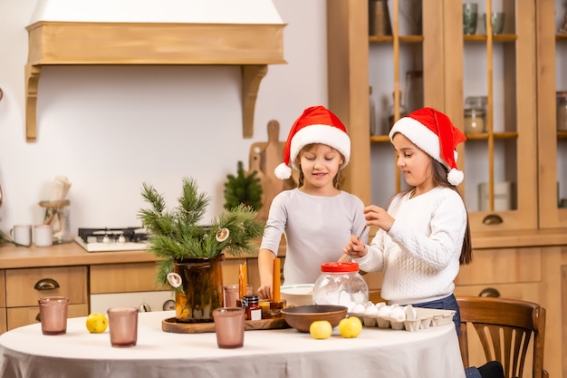 felizes irmãs crianças meninas duas meninas cozinhando antes do natal na cozinha