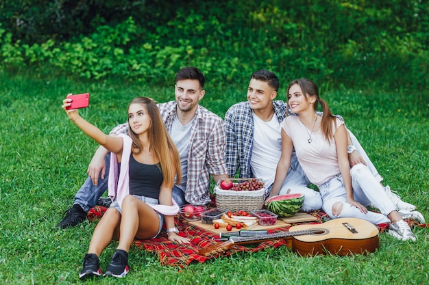 Felizes jovens amigos fazendo piquenique no parque.