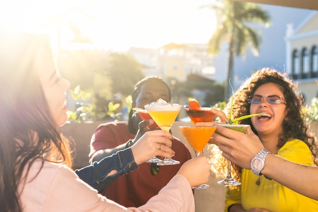 Felizes jovens amigos se divertindo lá fora e brindando com coquetéis juntos Concentre-se nos copos