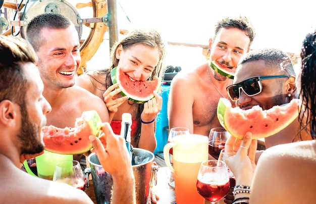 Felizes jovens amigos se divertindo na festa do barco com sangria de melancia e vinho champanhe